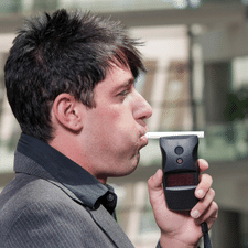 Man blowing into handheld breath test